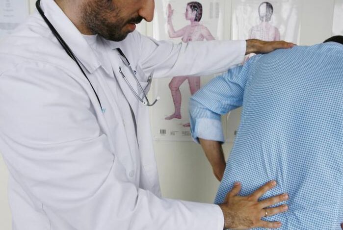 O doutor examina a un paciente con dor nas costas na rexión lumbar